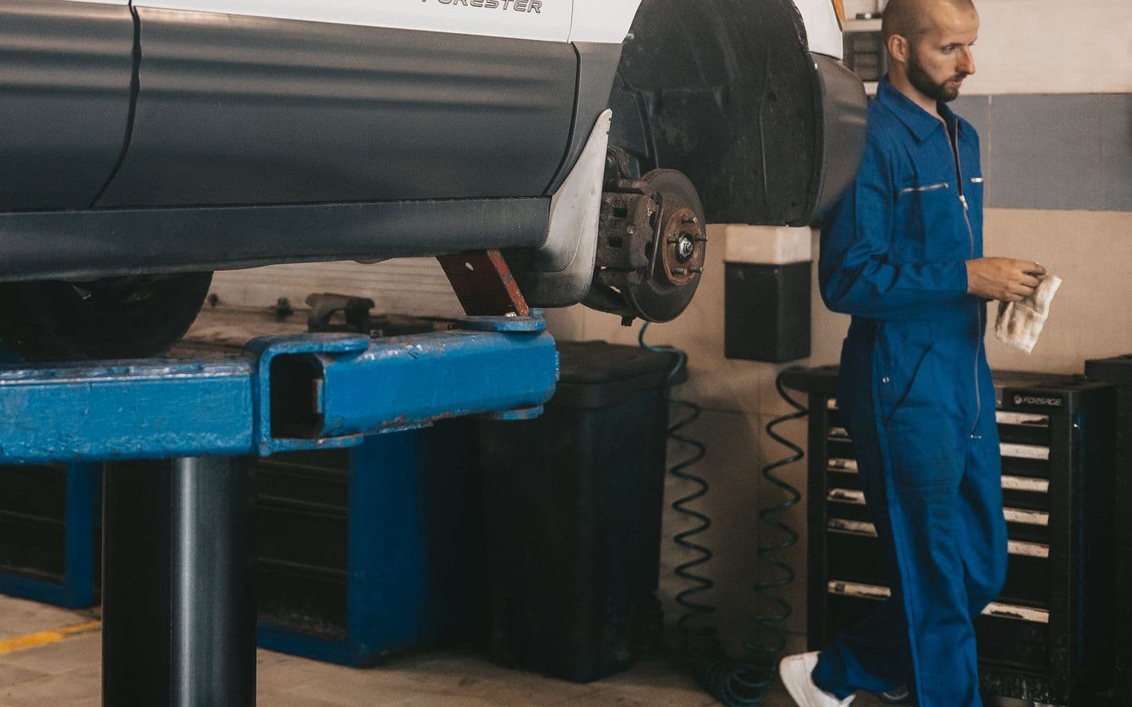 A mechanic inspecting an engine bay with the bonnet open
